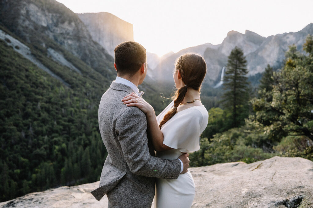 Couple embracing at Yosemite sunrise overlook with Half Dome and valley views in the background